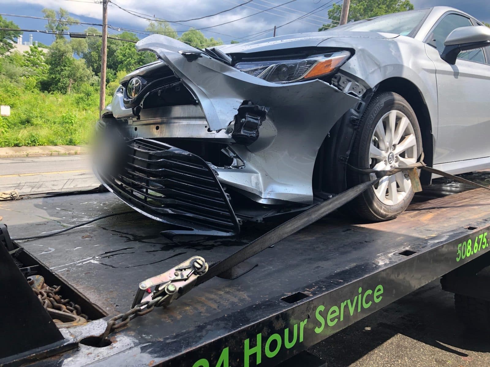 Collision-damaged sedan strapped to the flatbed