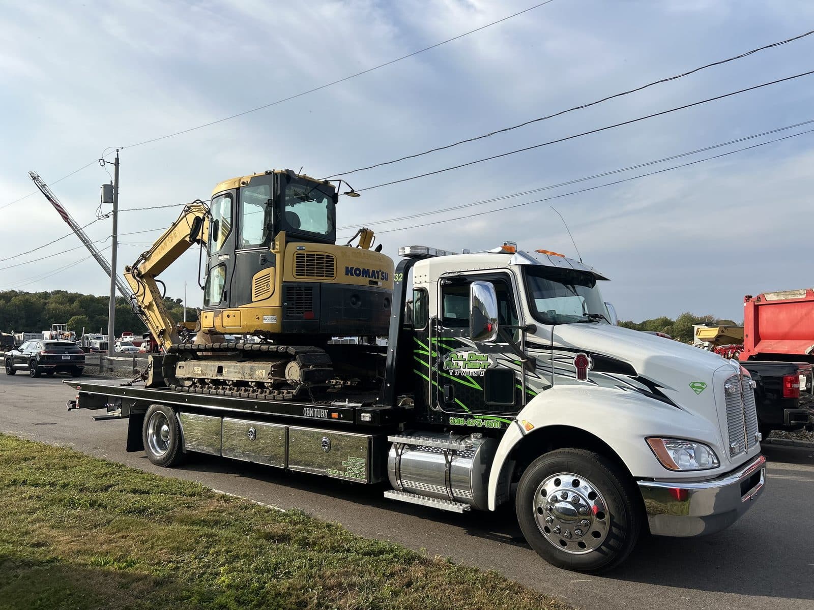 Kenworth flatbed tow truck carrying a tracked excavator