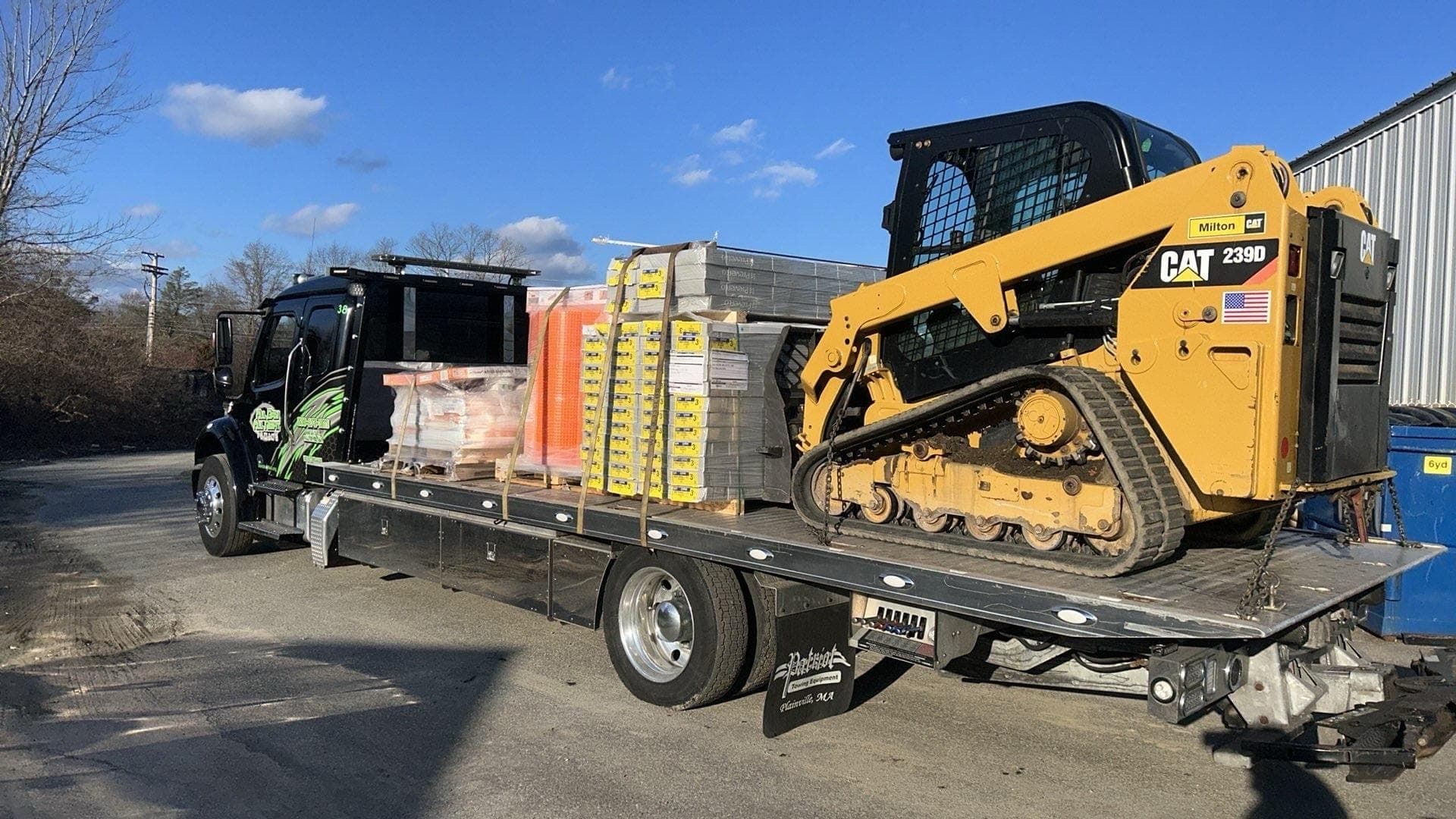 Skid steer and pallets of building materials on the flatbed