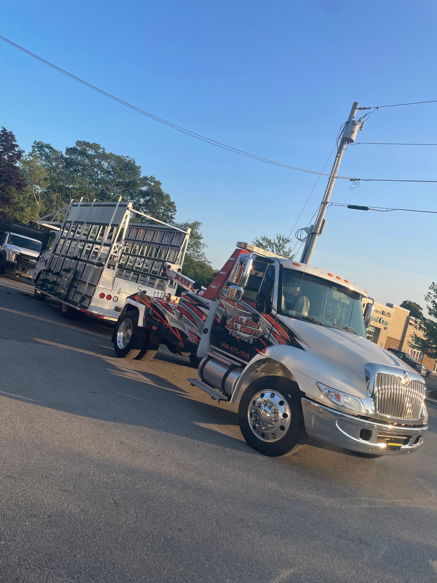 Stake-body truck under tow behind the wrecker